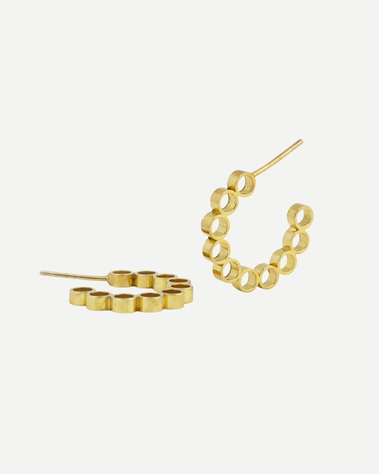 Gold hoop earrings with circle design and contemporary aesthetic on white background