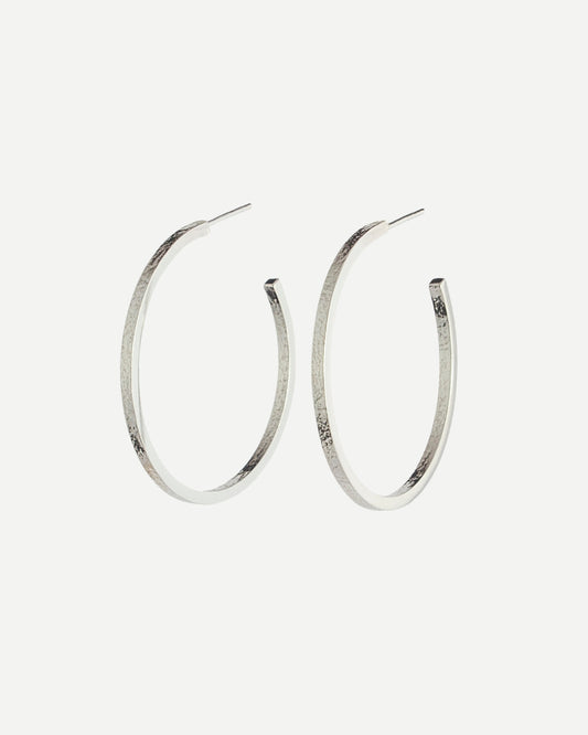 Large sterling silver hoop earrings with delicate texture on front and back on white background