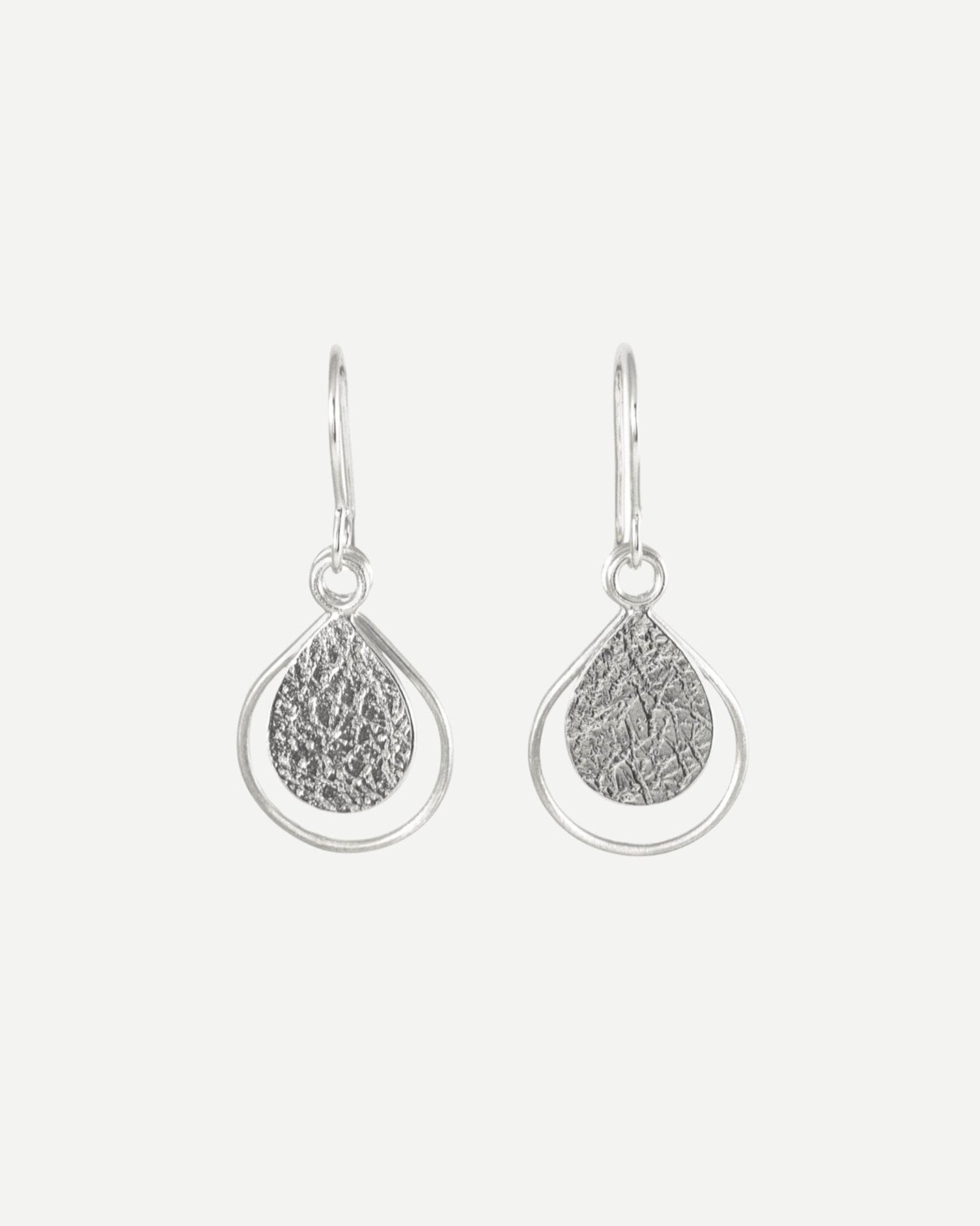 Sterling silver earrings consisting of textured teardrops framed with thin wire teardrops hanging from handmade silver hooks