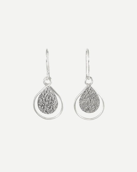 Sterling silver earrings consisting of textured teardrops framed with thin wire teardrops hanging from handmade silver hooks