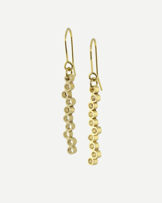Long gold dangly earrings with circle design hanging from gold earring hooks