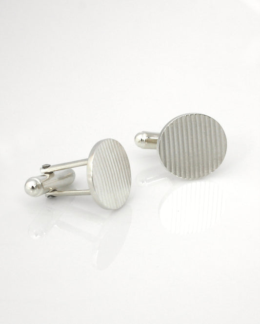 Silver oval cufflinks with ribbon texture on reflective white background