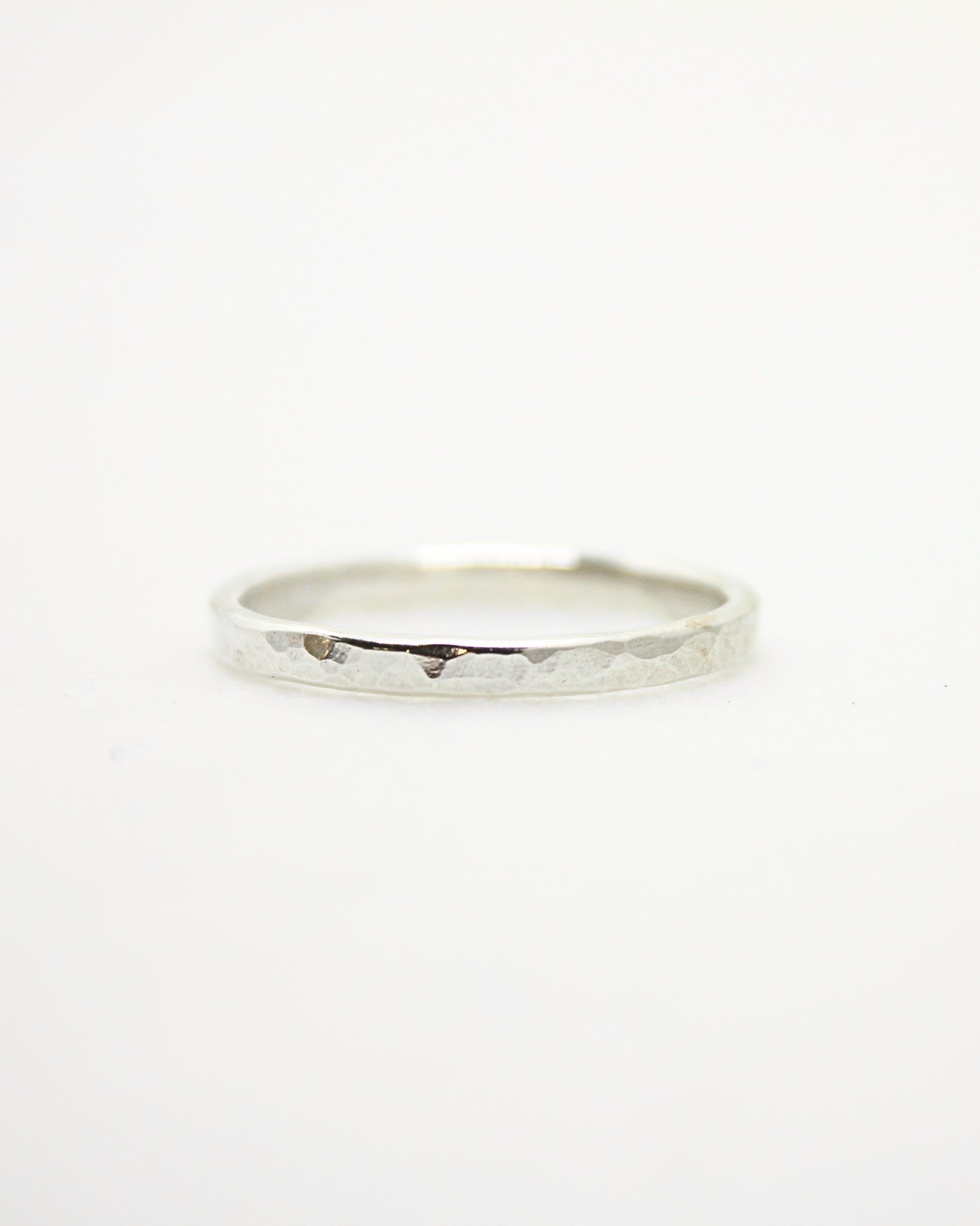 Dainty sterling silver stacking ring with reflective dimpled surface texture on white background