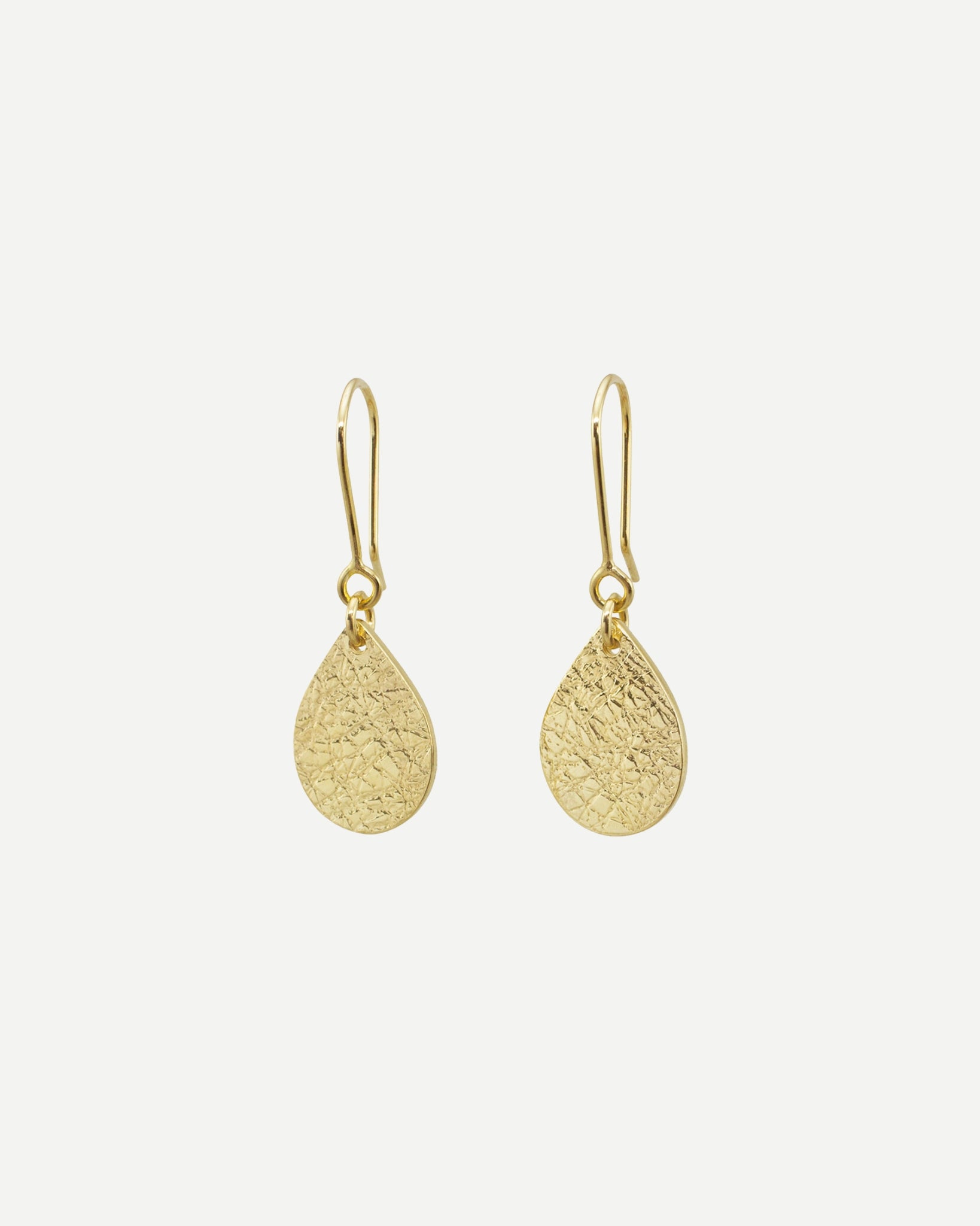 Elegant textured gold teardrops hanging from handmade gold earring hooks on white background