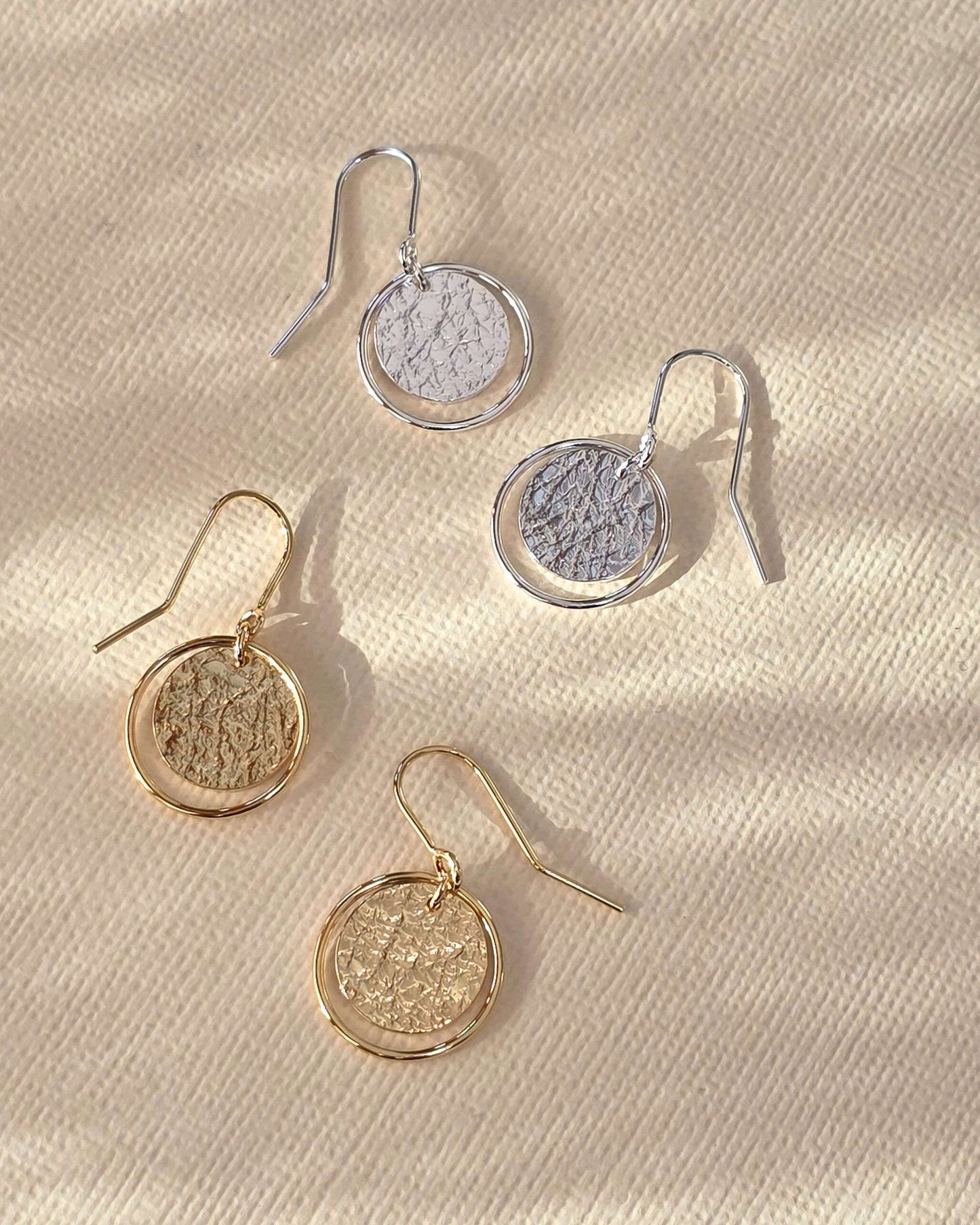 handmade textured gold and silver circle earrings on paper background