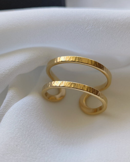 Handmade textured gold double band adjustable ring lying on white fabric