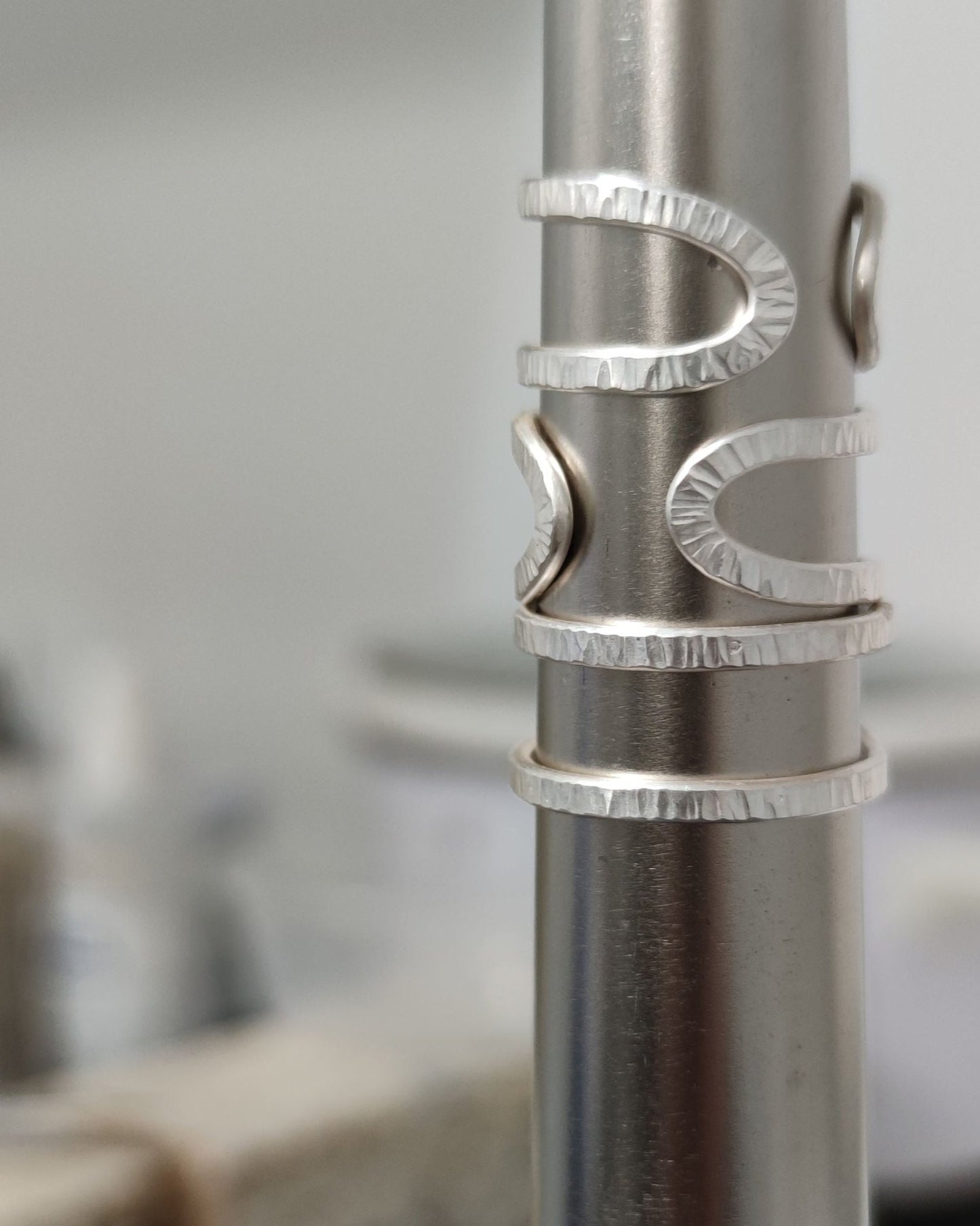 Three silver double band rings with hammered texture on steel mandrel with blurred background