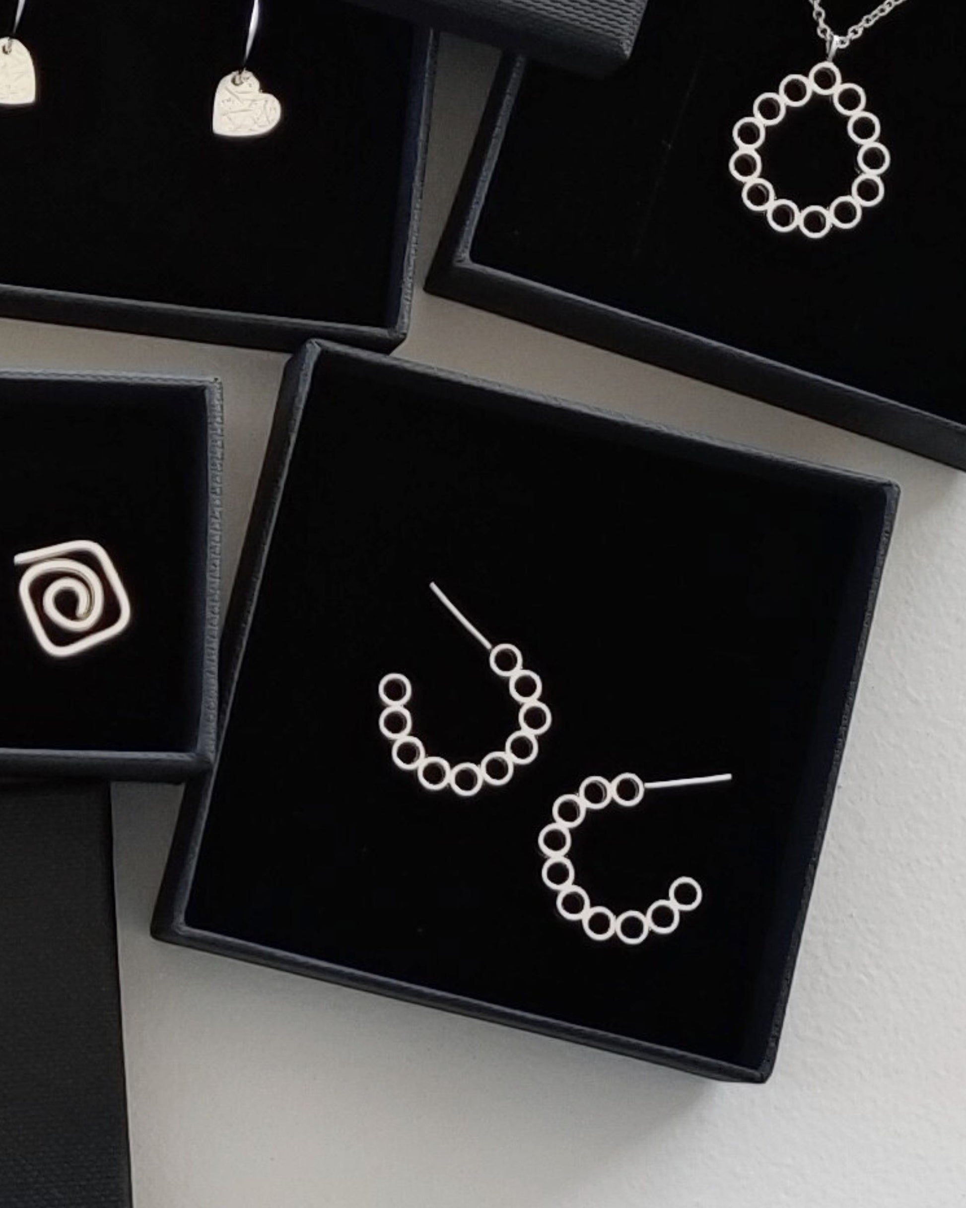 Close up of sterling silver jewellery with a geometric aesthetic lying in black jewellery gift boxes