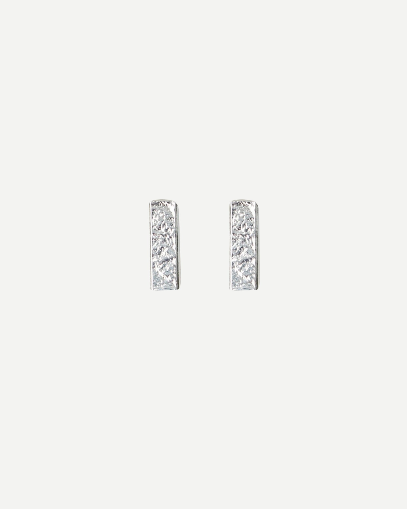 Front view of small textured rectangle stud earrings on white background