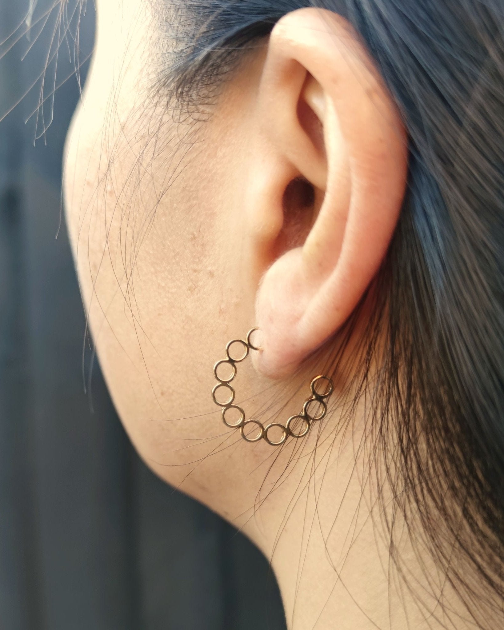 Side view of person wearing handmade gold hoop earrings made from multiple small circles