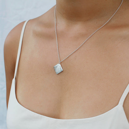 model wearing minimalist silver textured square necklace