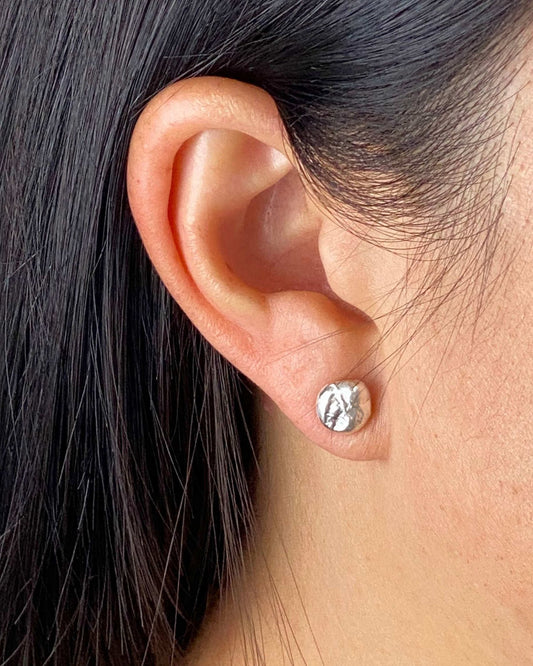 Person wearing nugget-shaped molten silver stud earring with textured surface