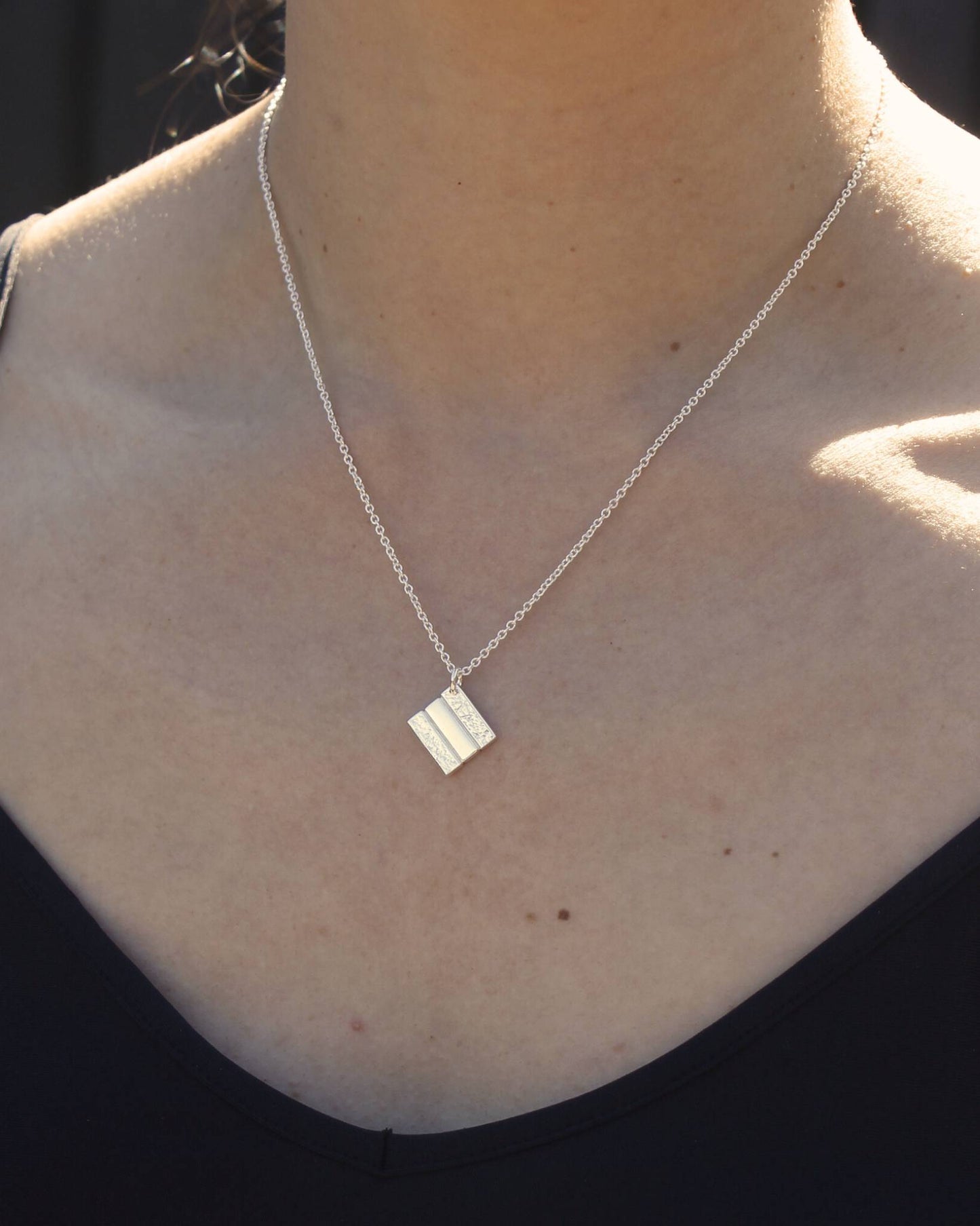 model wearing simple textured stack square pendant handmade in christchurch nz