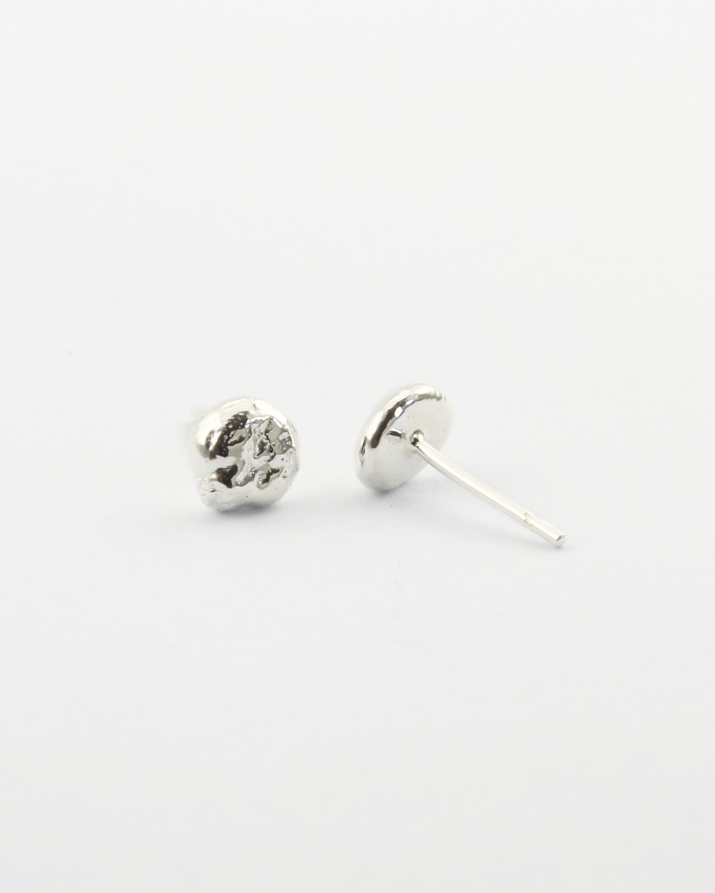 Small sterling silver circle-shaped stud earrings with off-white background