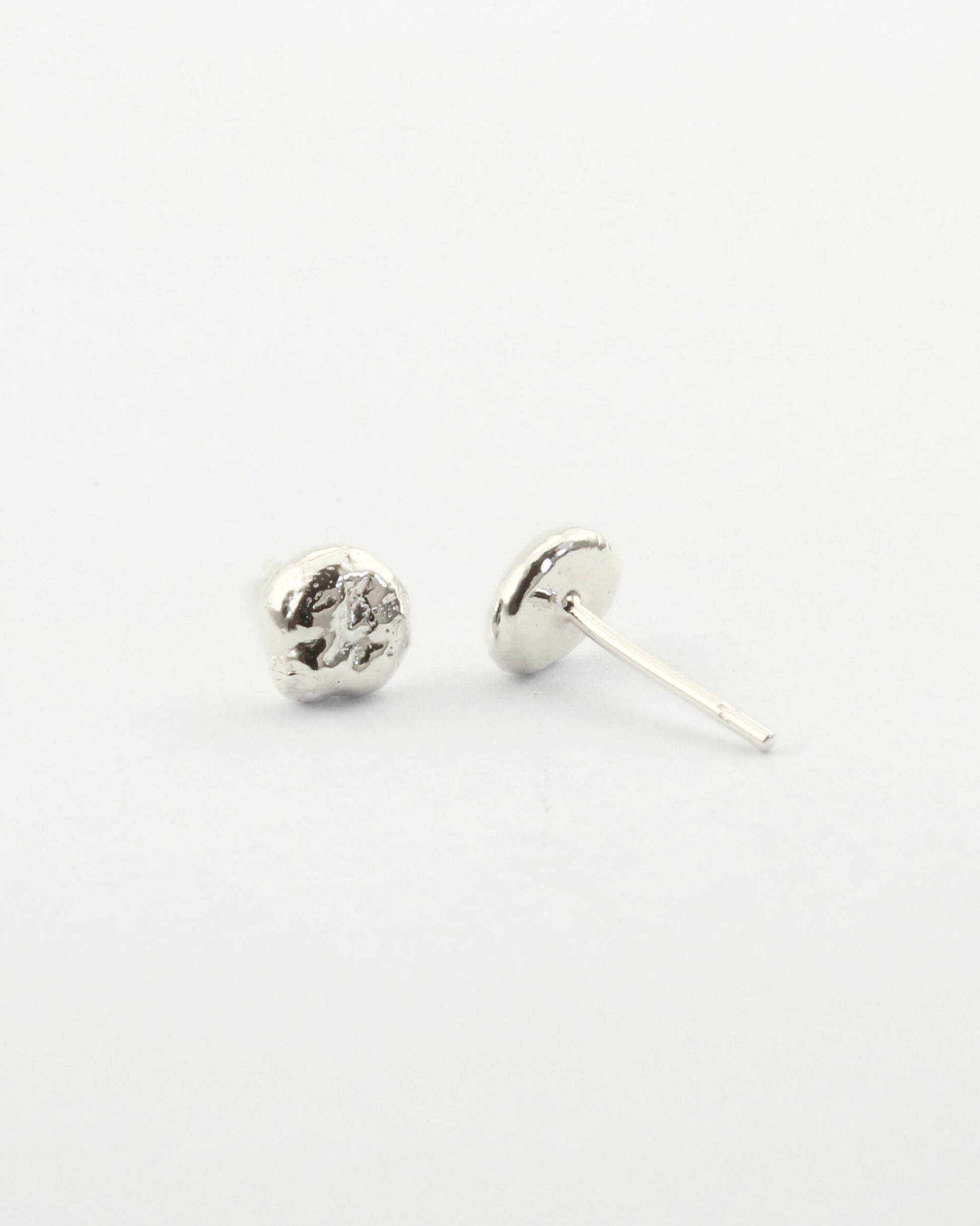Small sterling silver circle-shaped stud earrings with off-white background