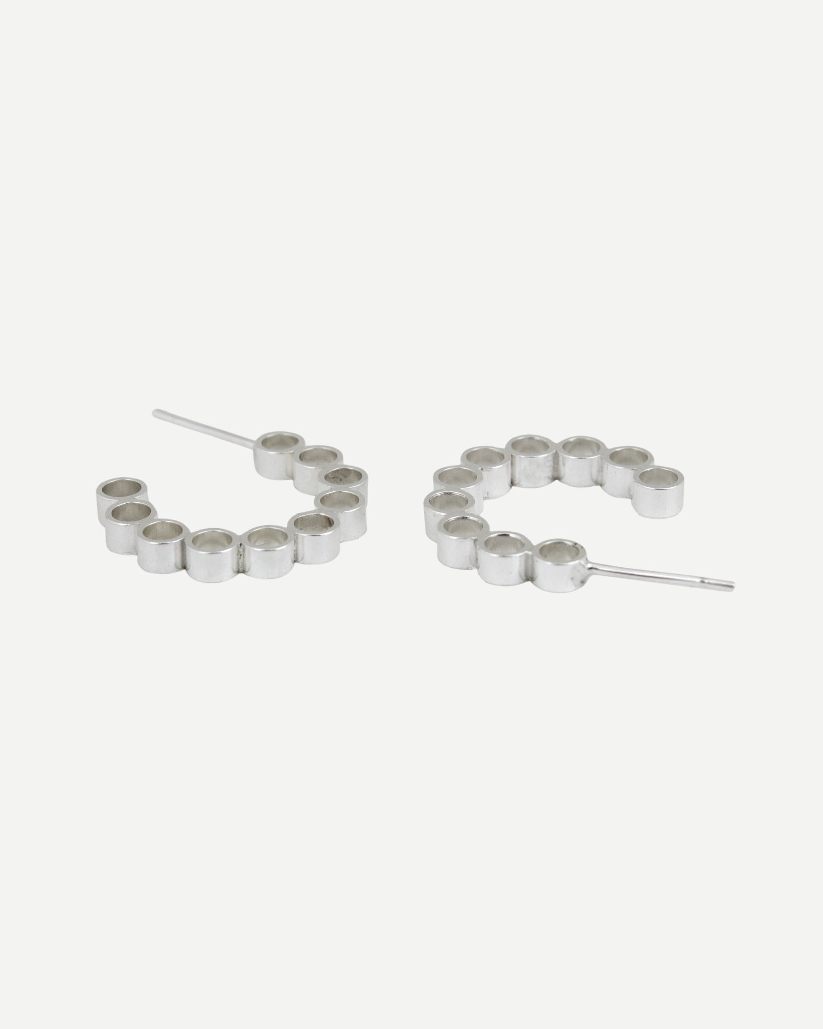 Sterling silver hoop earrings with circle design lying on white background