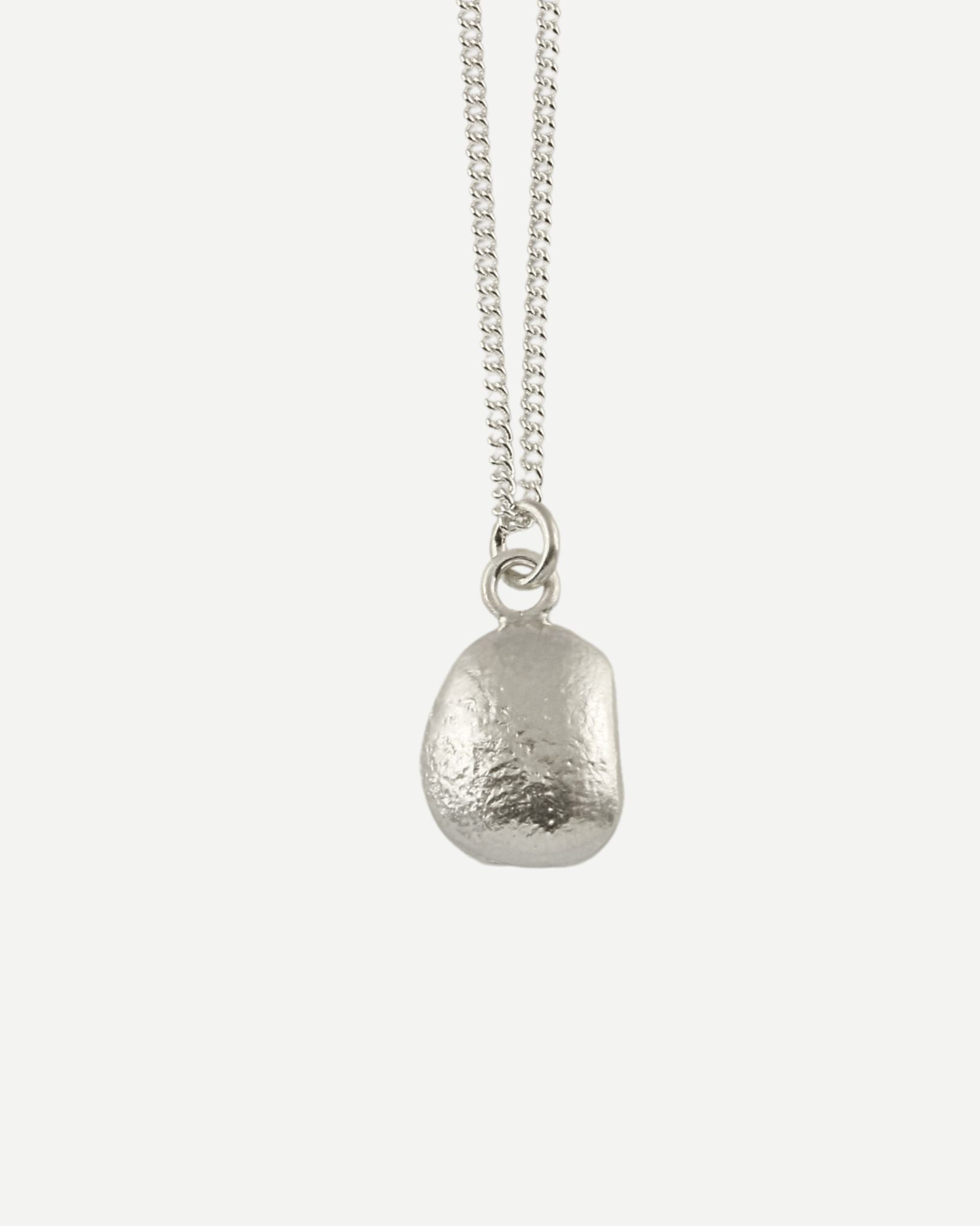 Front view of small molten silver pebble-shaped pendant hanging from fine silver curb chain with white background