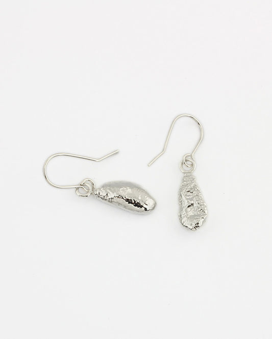 Long molten silver drop earrings hanging from handmade silver hooks on white background