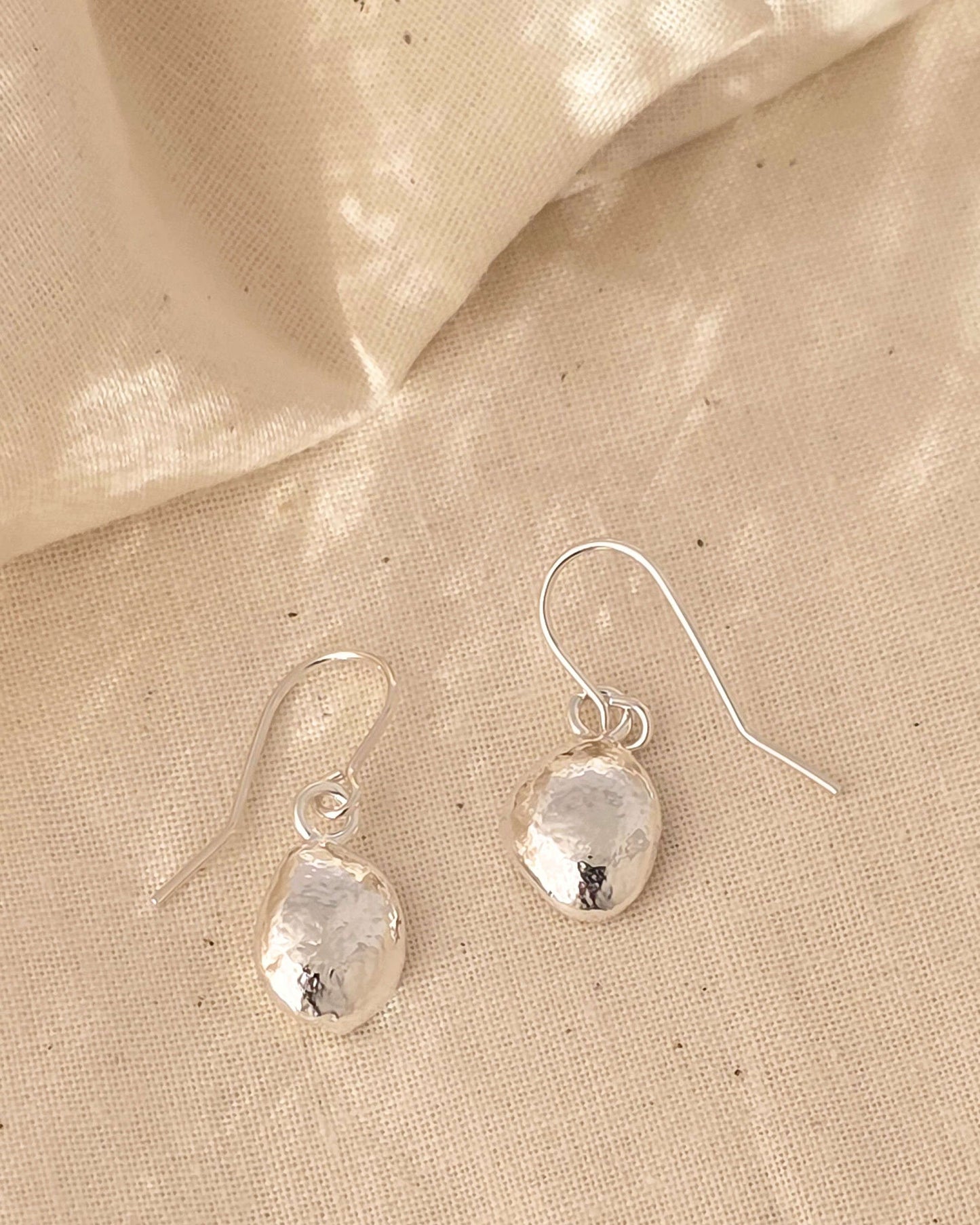 molten sterling silver teardrop earrings on a textured surface