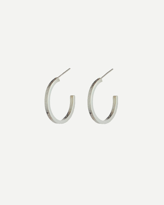 Silver hoop earrings with delicate texture on front and back, with off-white background