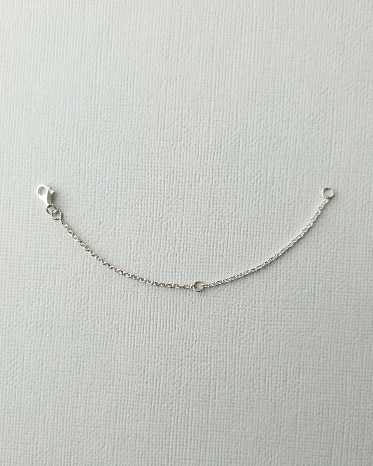 Sterling silver 10cm chain extender on textured paper background