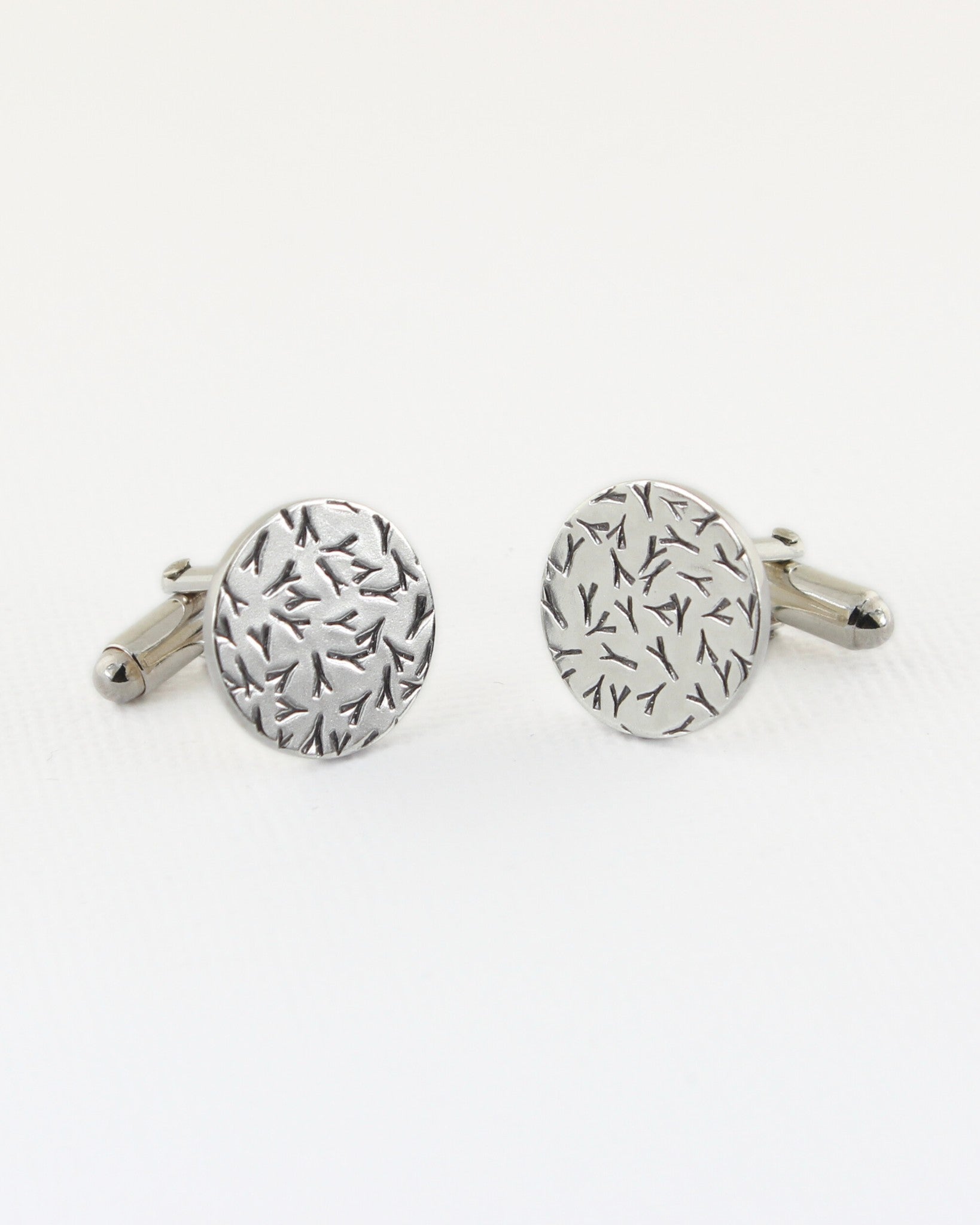 Silver circle cufflinks with contrasted silver and black surface on white background
