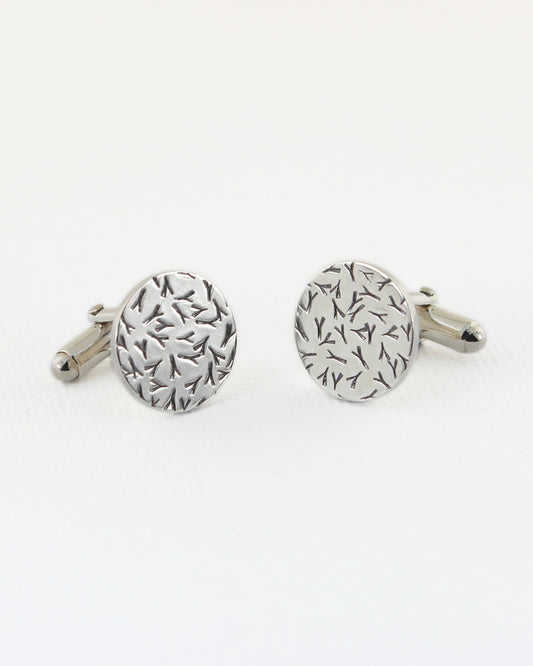 Silver circle cufflinks with contrasted silver and black surface on white background