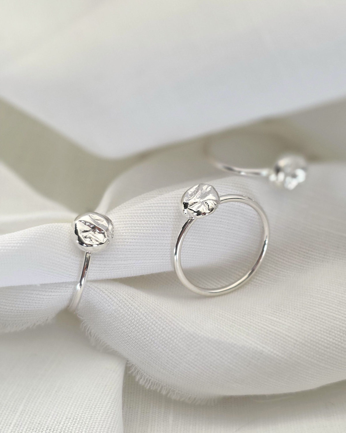 Three sterling silver rings with round molten nuggets on white fabric background