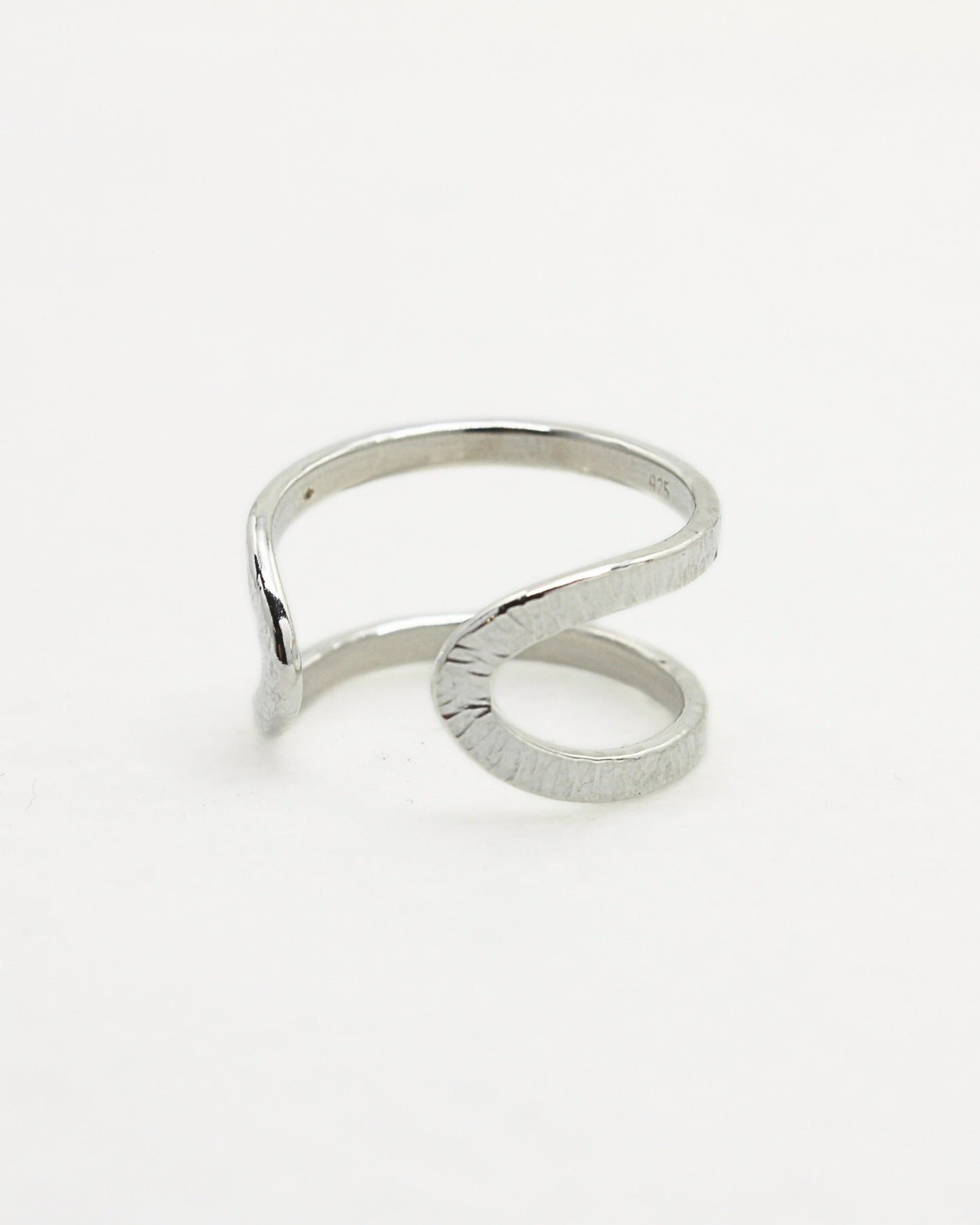Back view of textured adjustable silver ring in front of off-white background