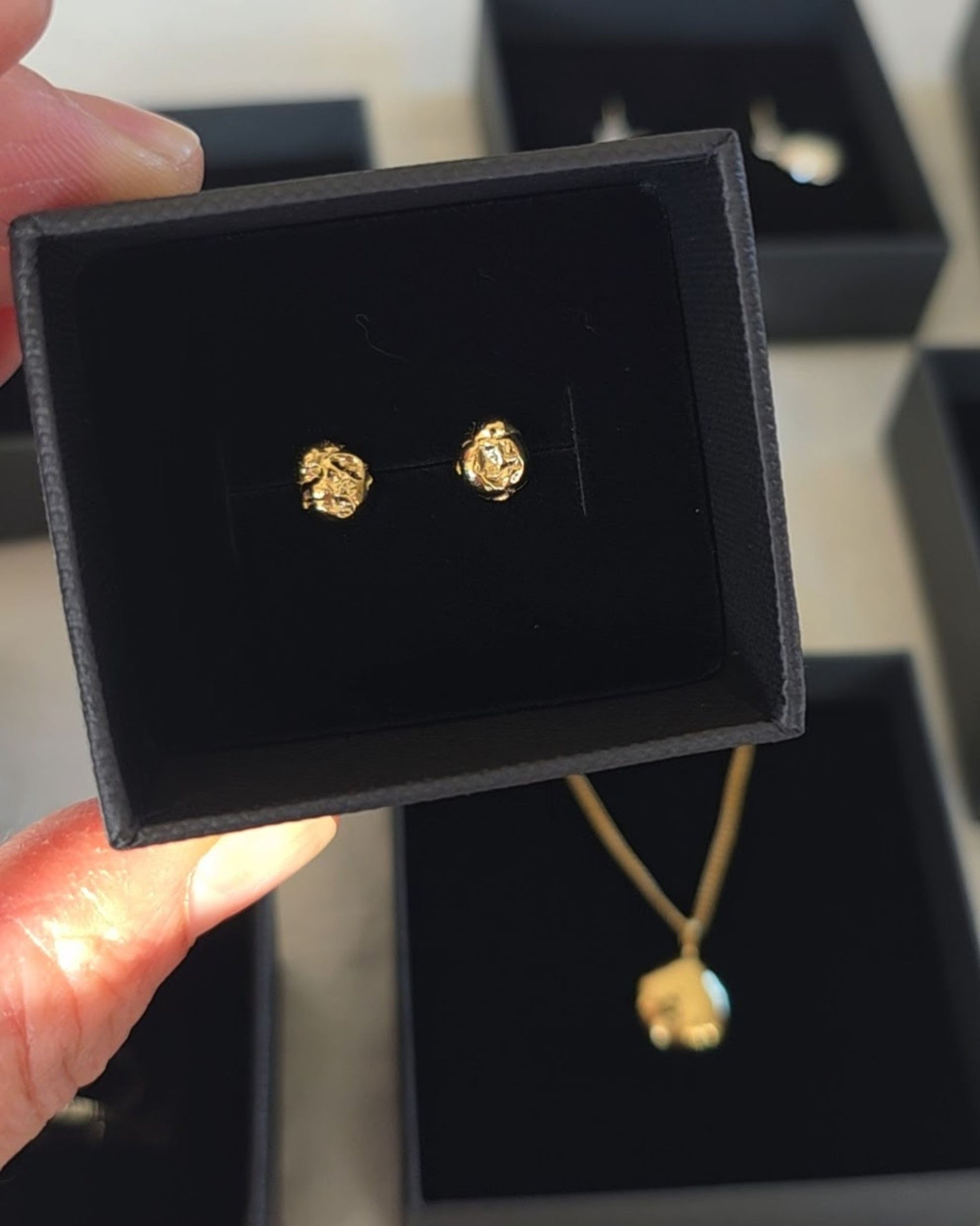 textured gold mini molten stud earrings in black gift box with gold molten pendant in background