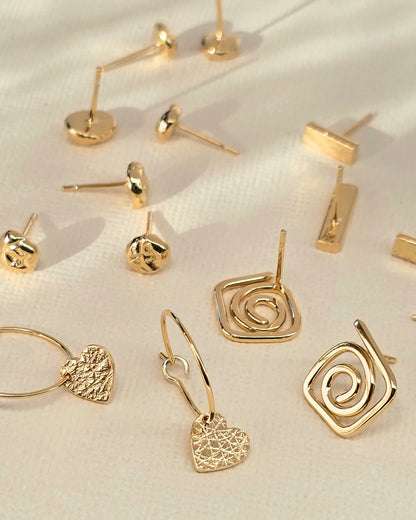 collection of delicate handcrafted gold studs on paper background