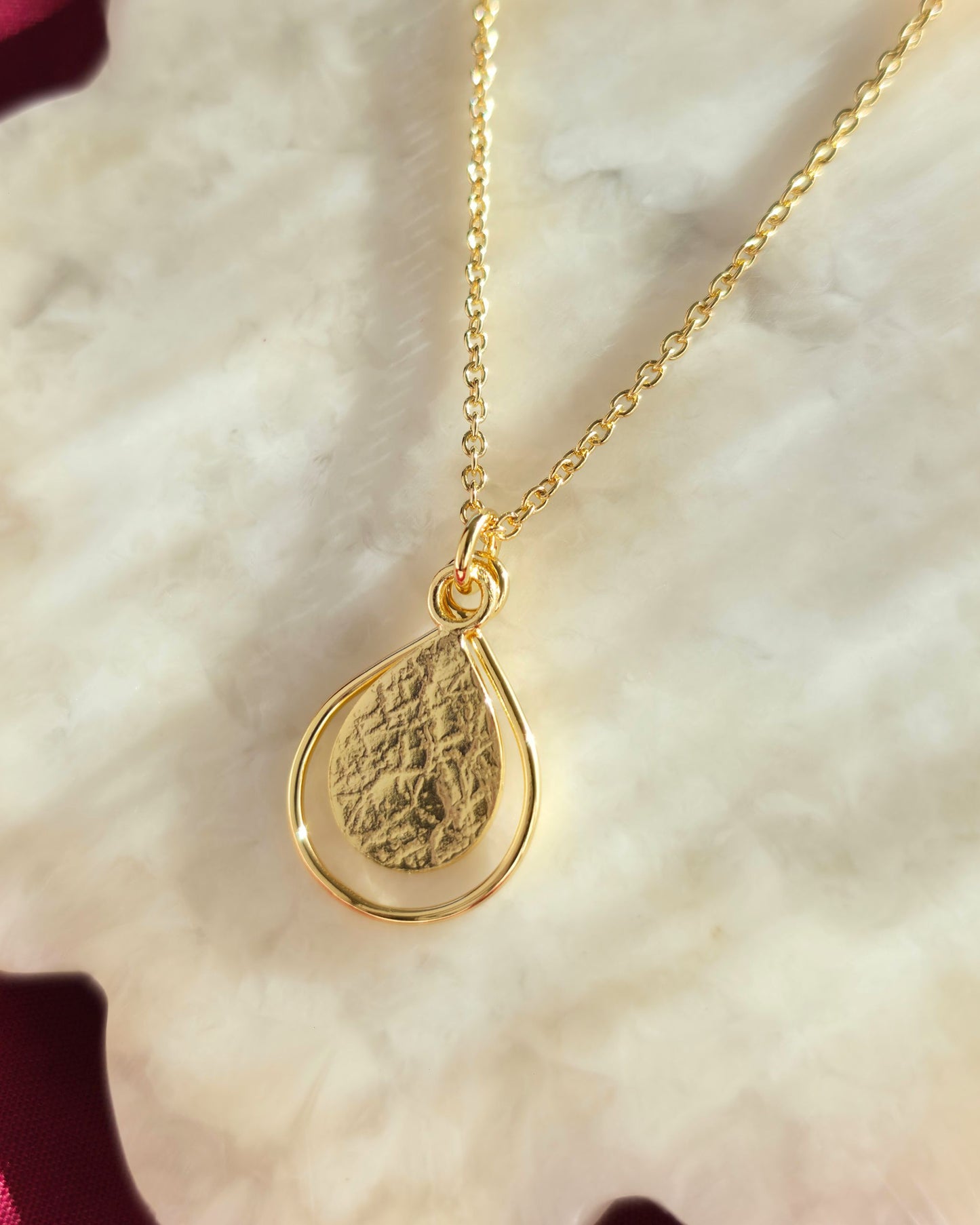 Gold teardrop pendant necklace on a light background