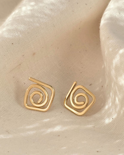 elegant gold diamond swirl spiral studs on cream textured background