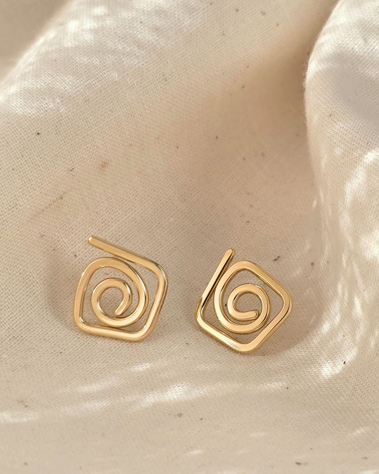 elegant gold diamond swirl spiral studs on cream textured background