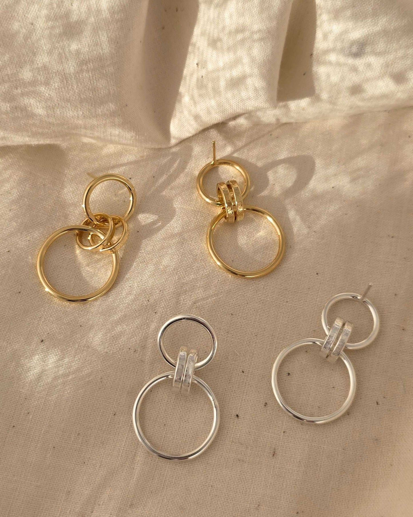 elegant handmade gold and silver link circle earrings lying in sunlight