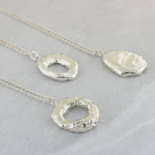 chunky organic silver molten necklaces on marble surface