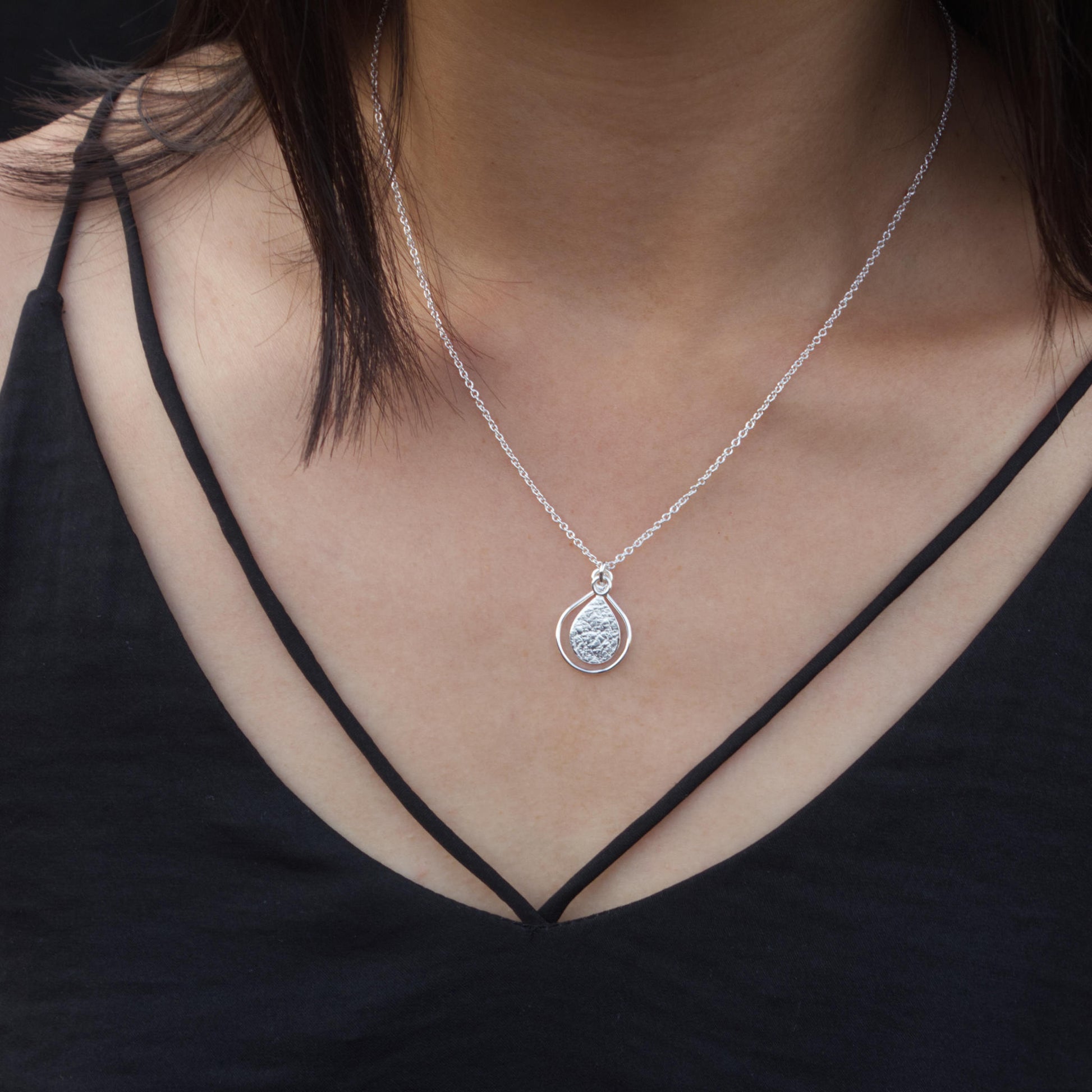 model wearing minimalist silver textured teardrop necklace
