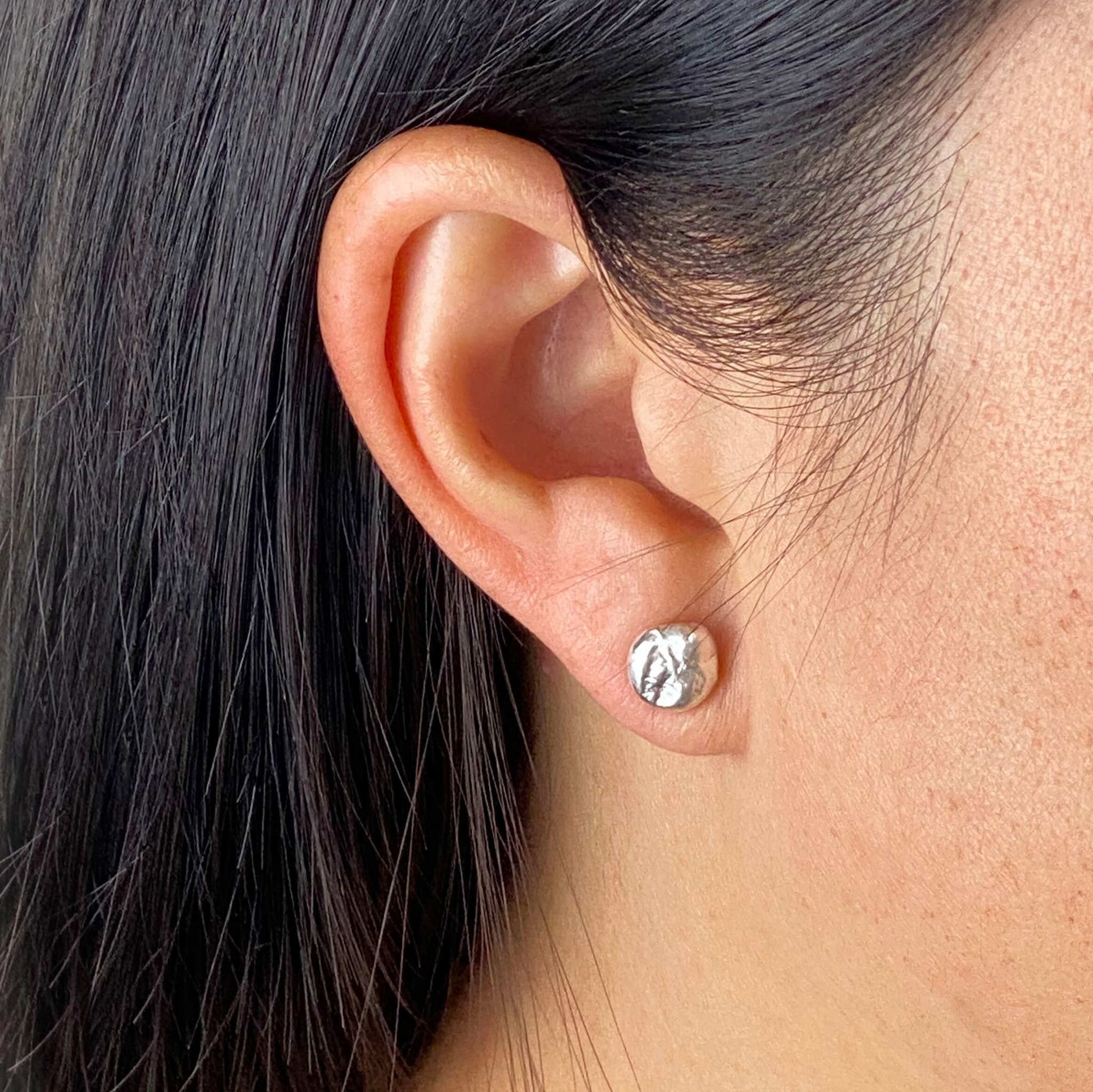 model wearing simple organic textured circle studs in sterling silver