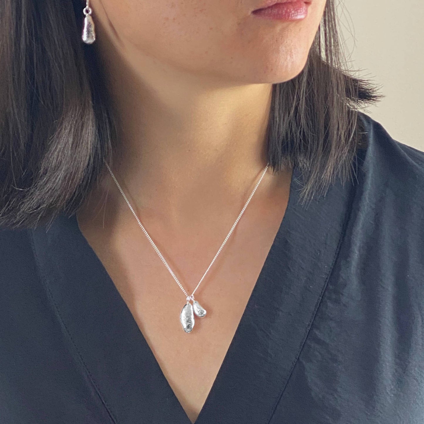 model wearing organic molten sterling silver droplet duo pendant