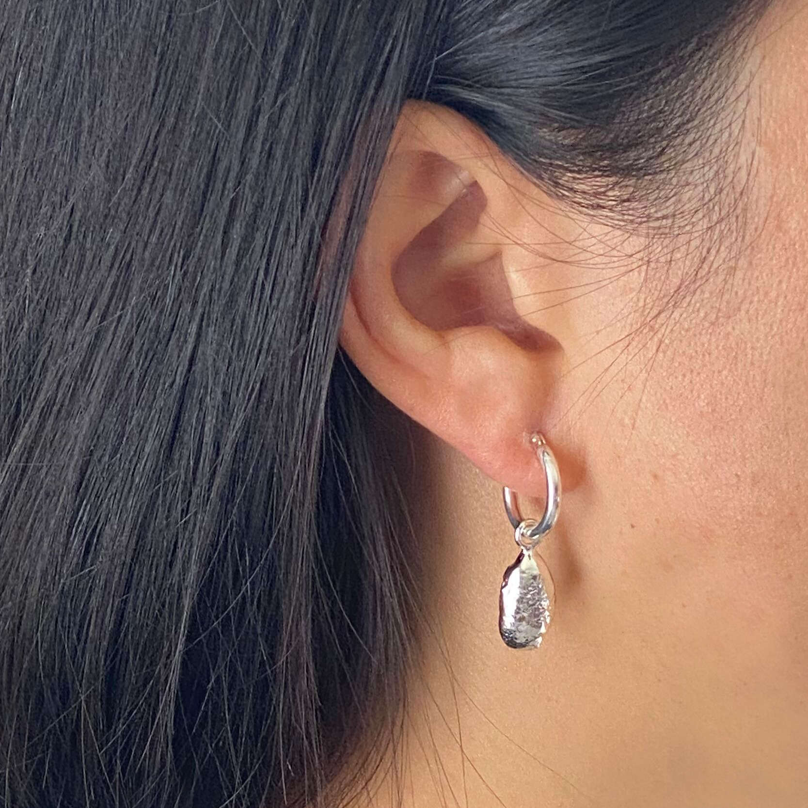 model wearing unique textured molten silver droplet earrings