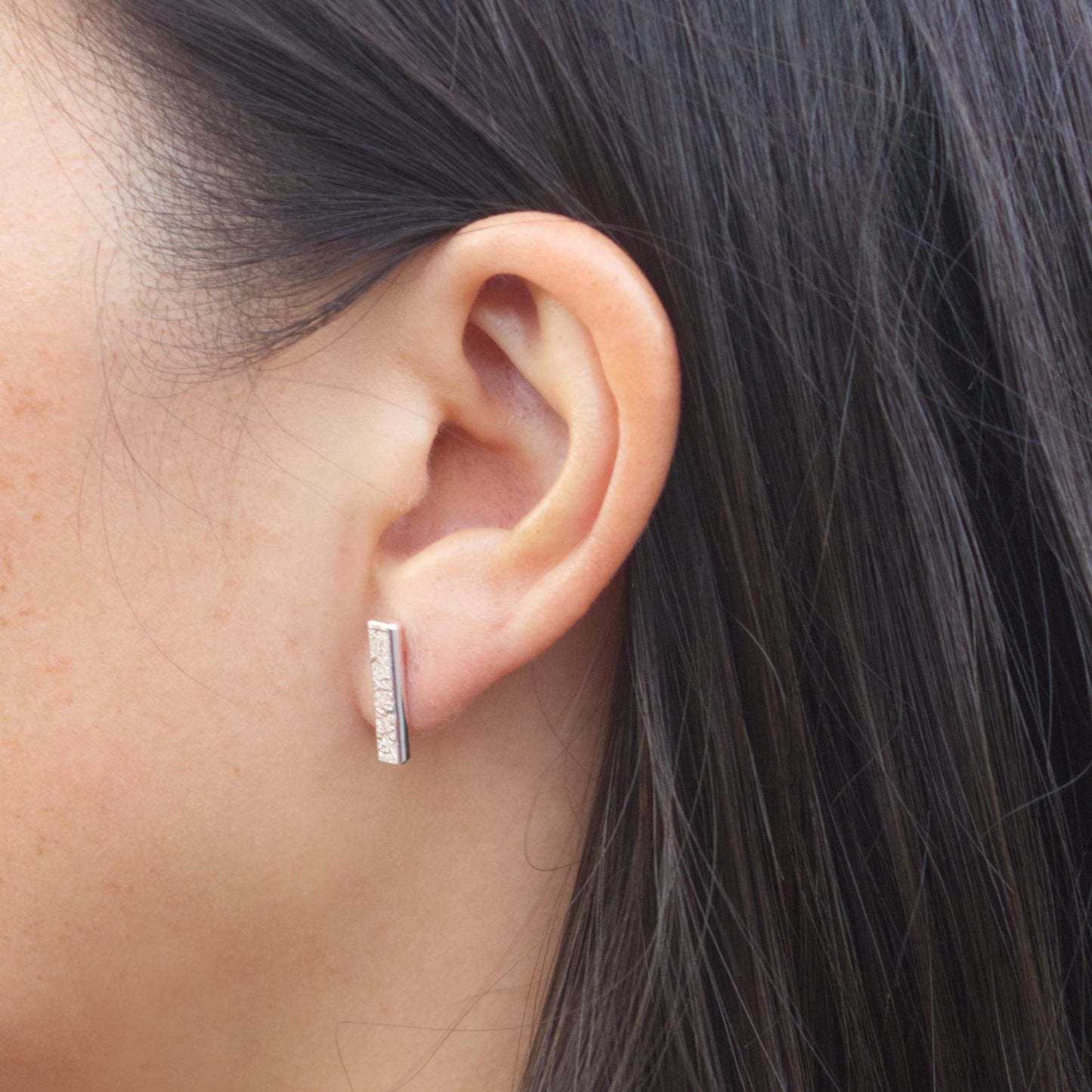 model wearing sterling silver textured bar earrings