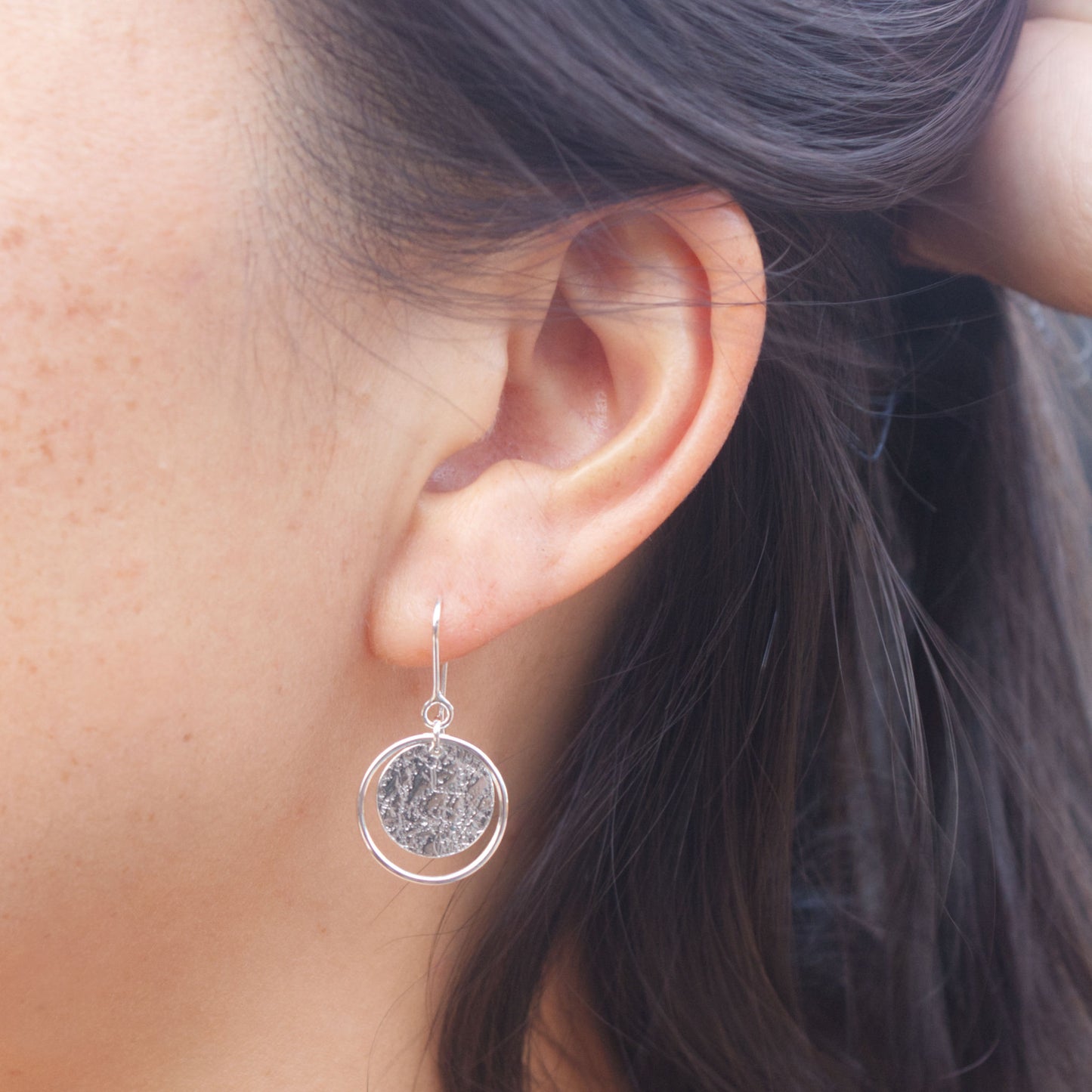 model wearing delicate everyday silver circle earrings on hooks