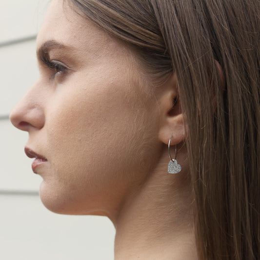 model wearing delicate sterling silver heart earrings on hoops