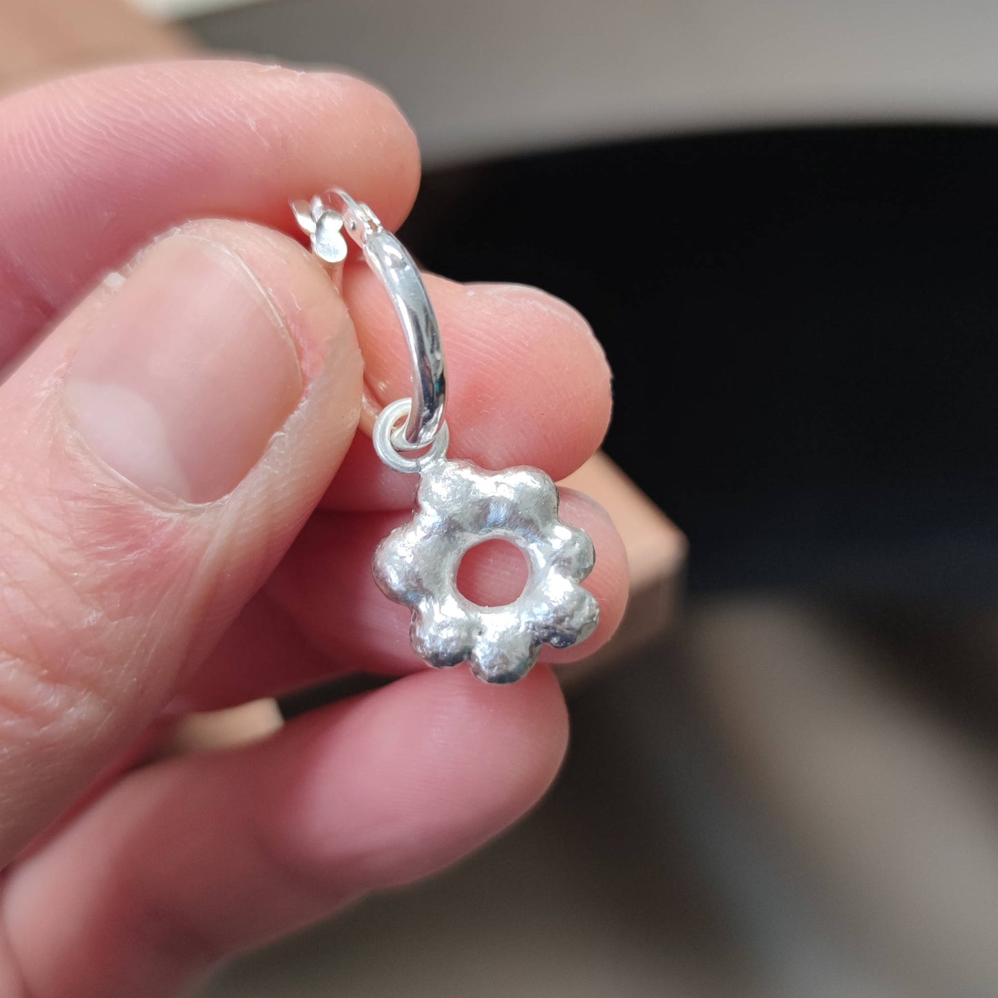 jeweller holding delicate freeform flower charm in sterling silver