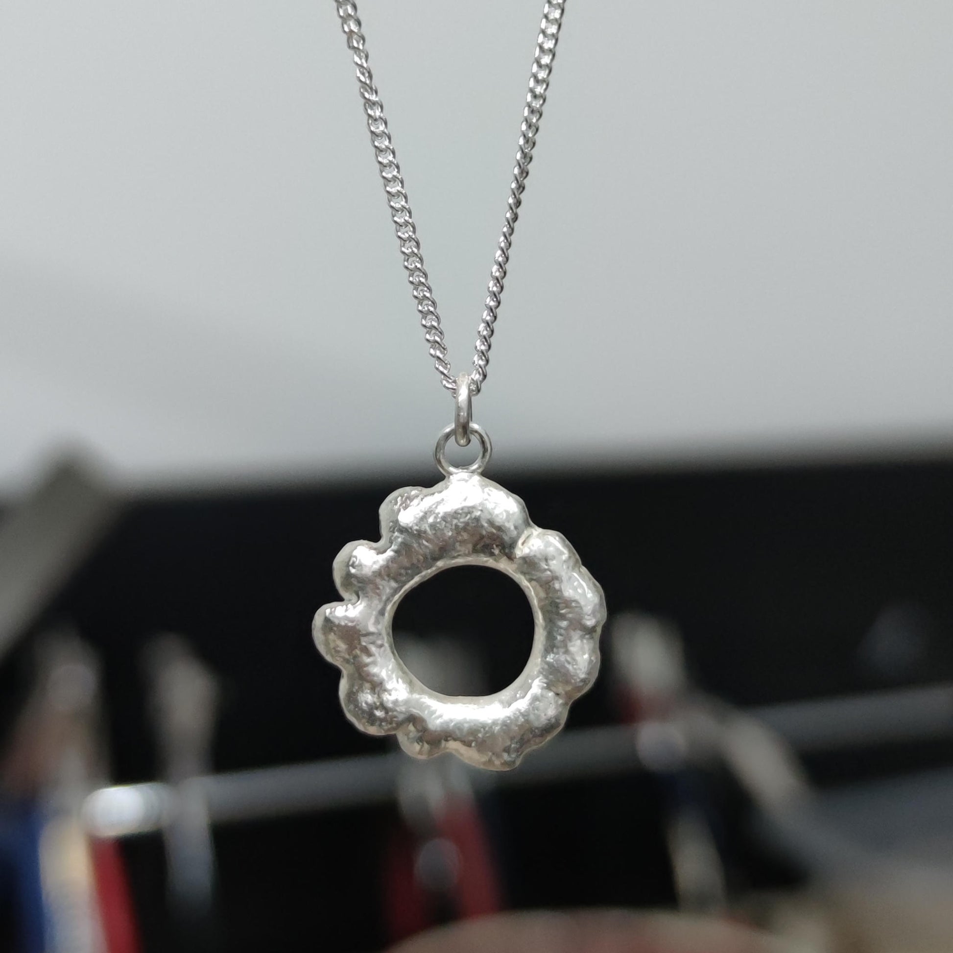 close up of organic textured molten silver loop pendant