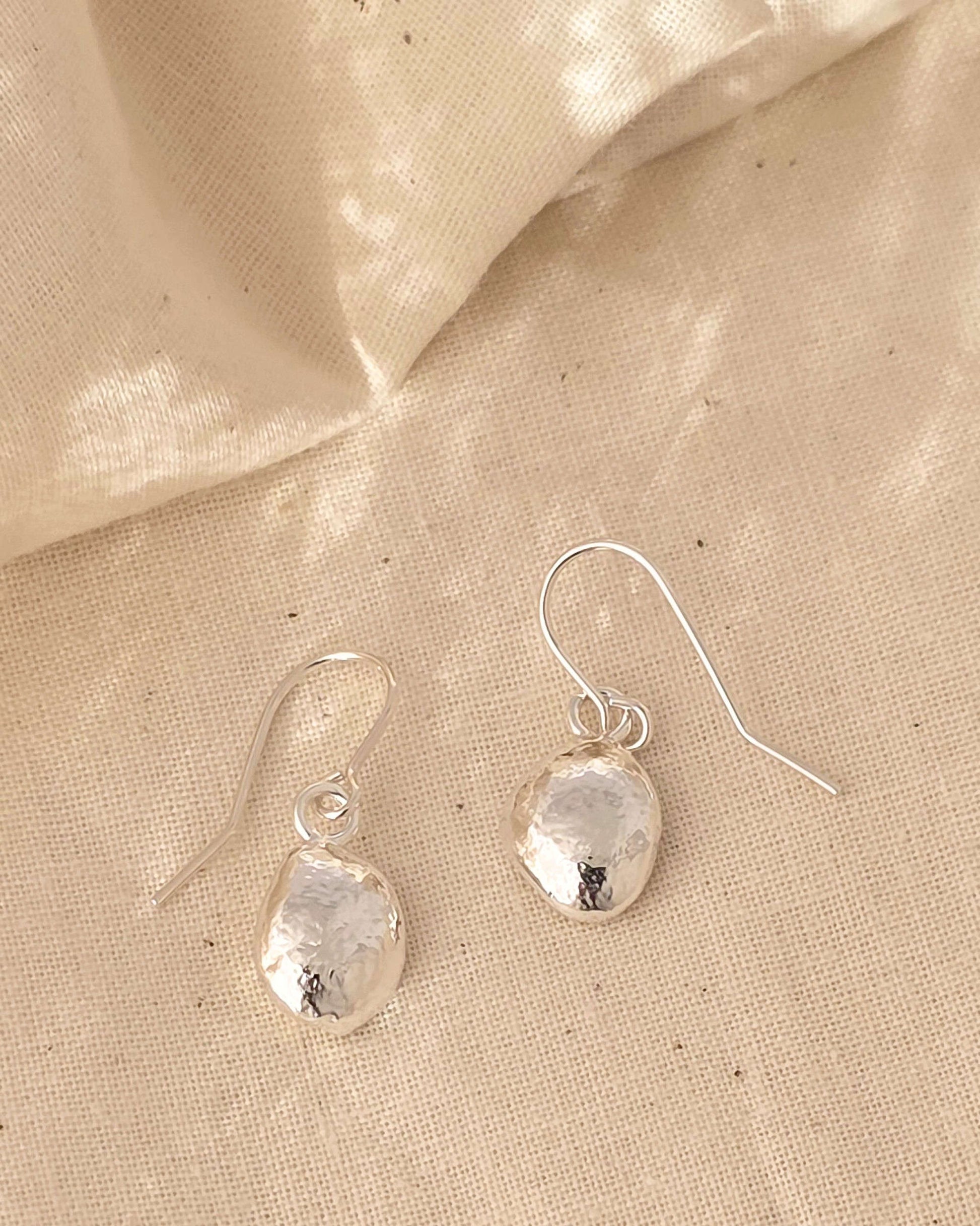 molten sterling silver teardrop earrings on a textured surface