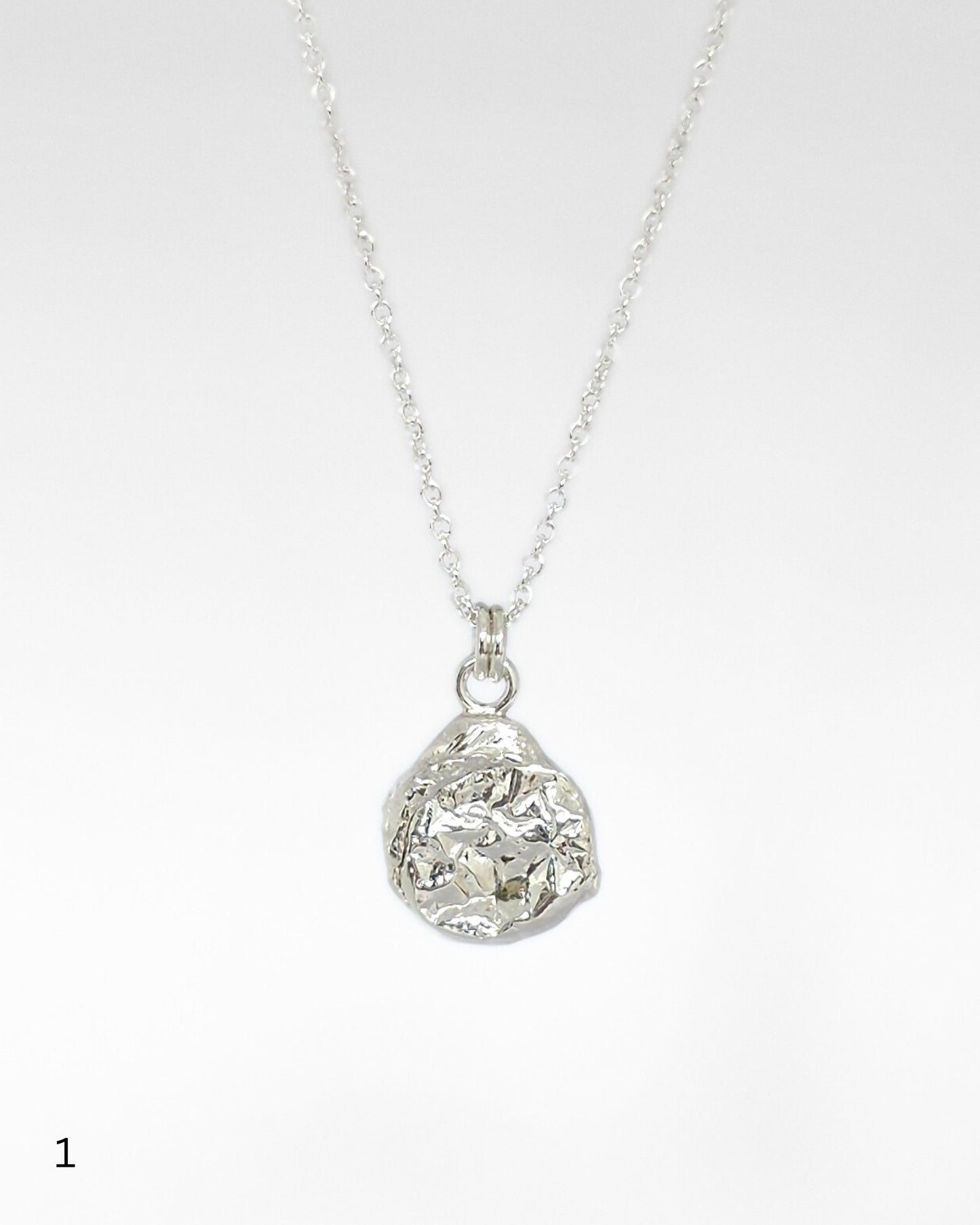 Sterling silver necklace with a textured molten pendant on a white background
