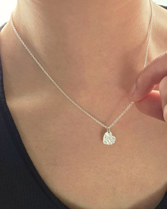 Close up of person wearing silver textured pendant necklace