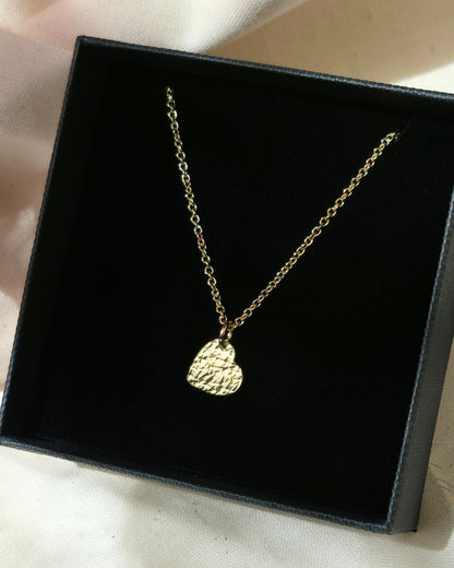 Gold necklace with a textured heart pendant in a black box