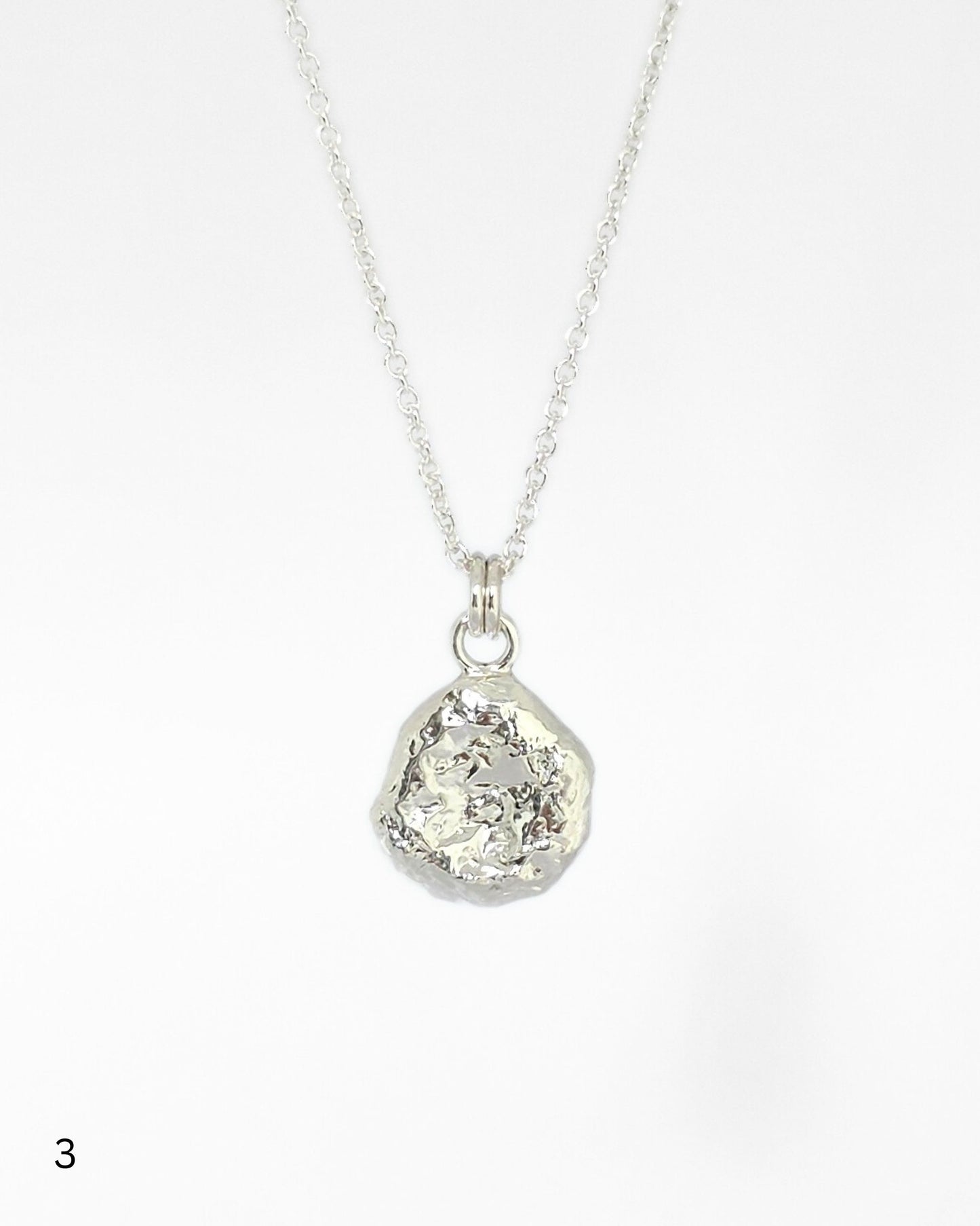 Sterling silver necklace with a textured pendant on a white background